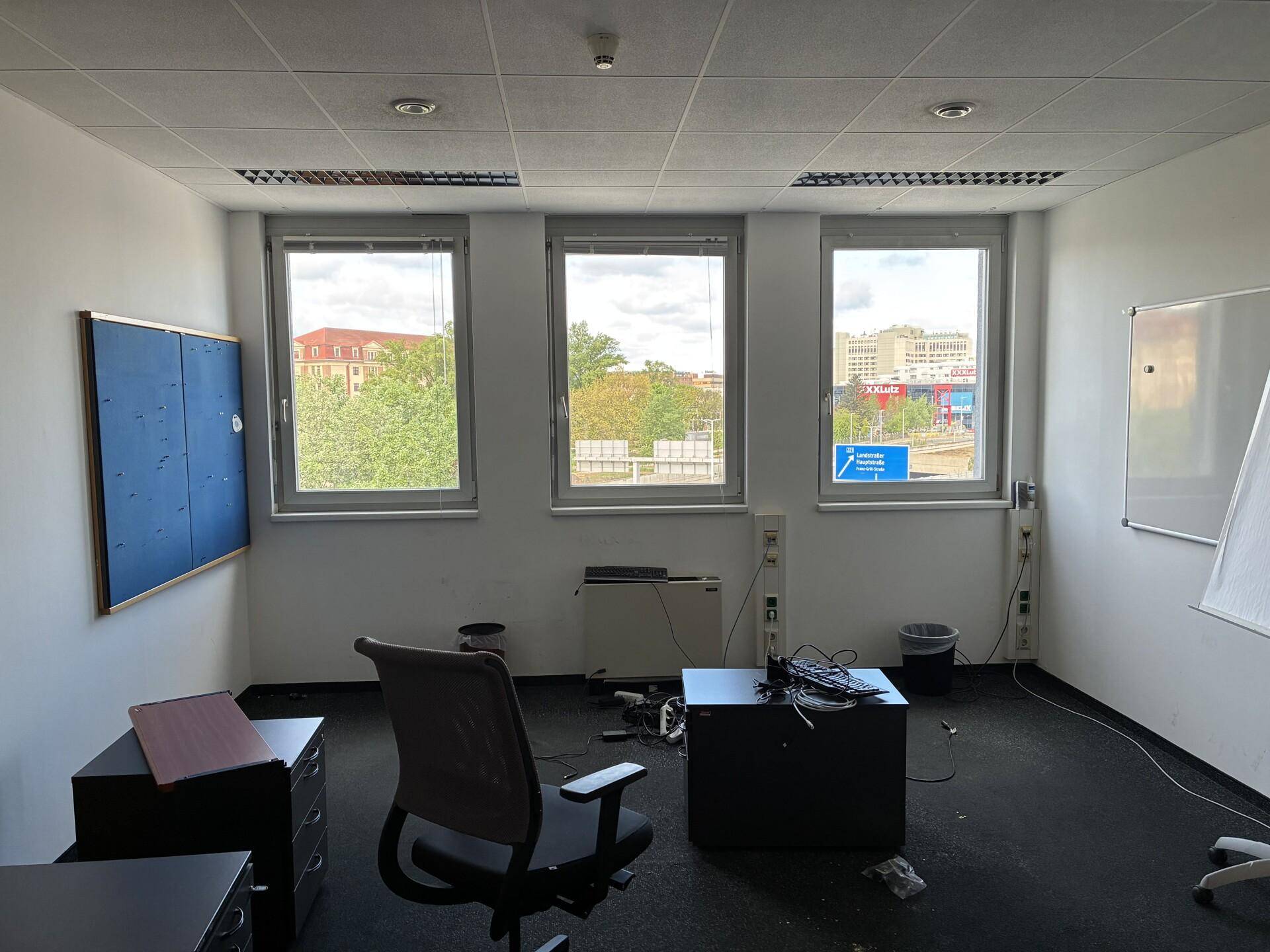 Büroraum mit Blick auf die Umgebung, ausgestattet mit einem Whiteboard und Pinnwand.