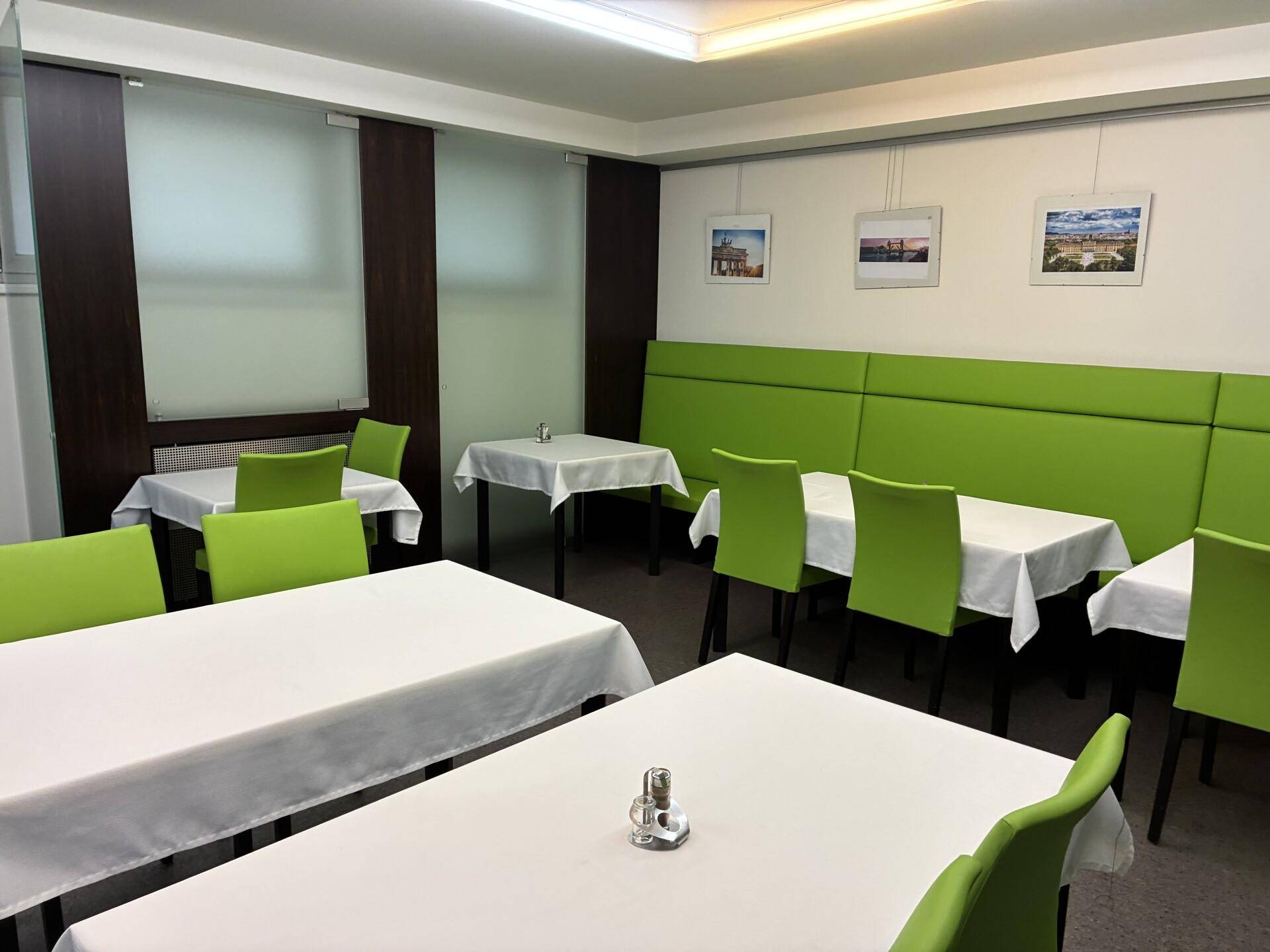 Helle Kantine mit grünen Sitzbänken und Tischen, bereit für Mahlzeiten.