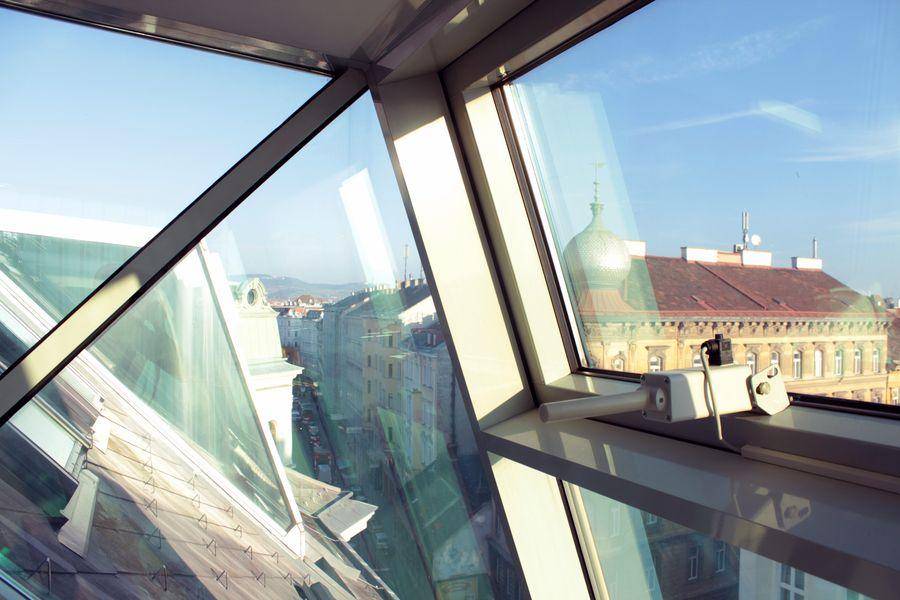 Panoramablick aus großen Glasfenstern auf die historische Stadtarchitektur und Dächer.