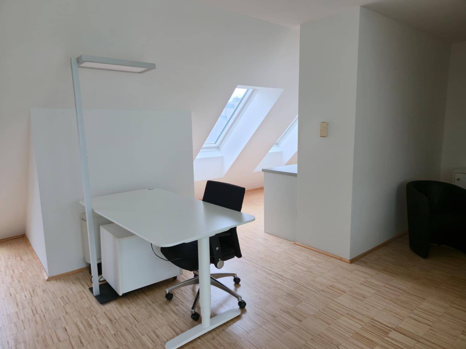 Heller Arbeitsplatz im Dachgeschoss mit Schreibtisch, Bürostuhl und Dachfenstern.