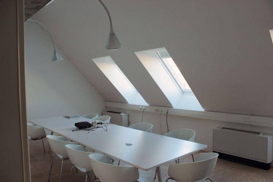 Konferenzraum im Dachgeschoss mit langem Tisch, vielen Stühlen und schrägen Dachfenstern.