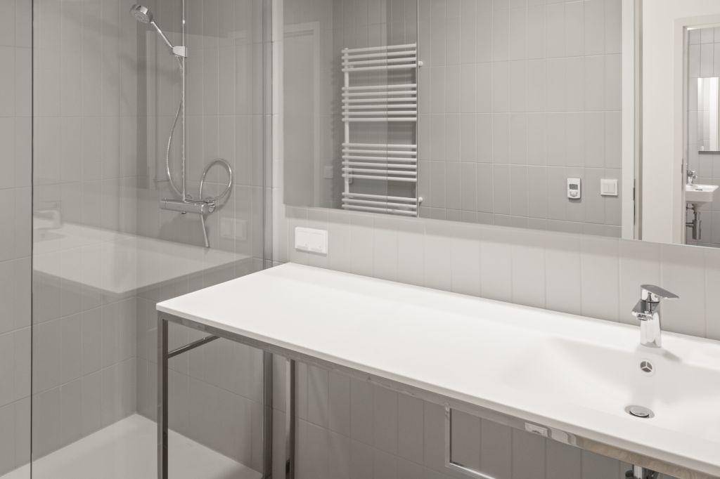 Helles, modernes Badezimmer mit Dusche, Waschbecken und beheiztem Handtuchhalter.