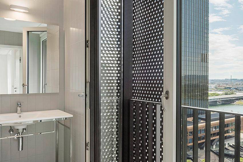 Modernes Badezimmer mit Waschbecken und Blick auf die Stadt durch die großen Fenster.