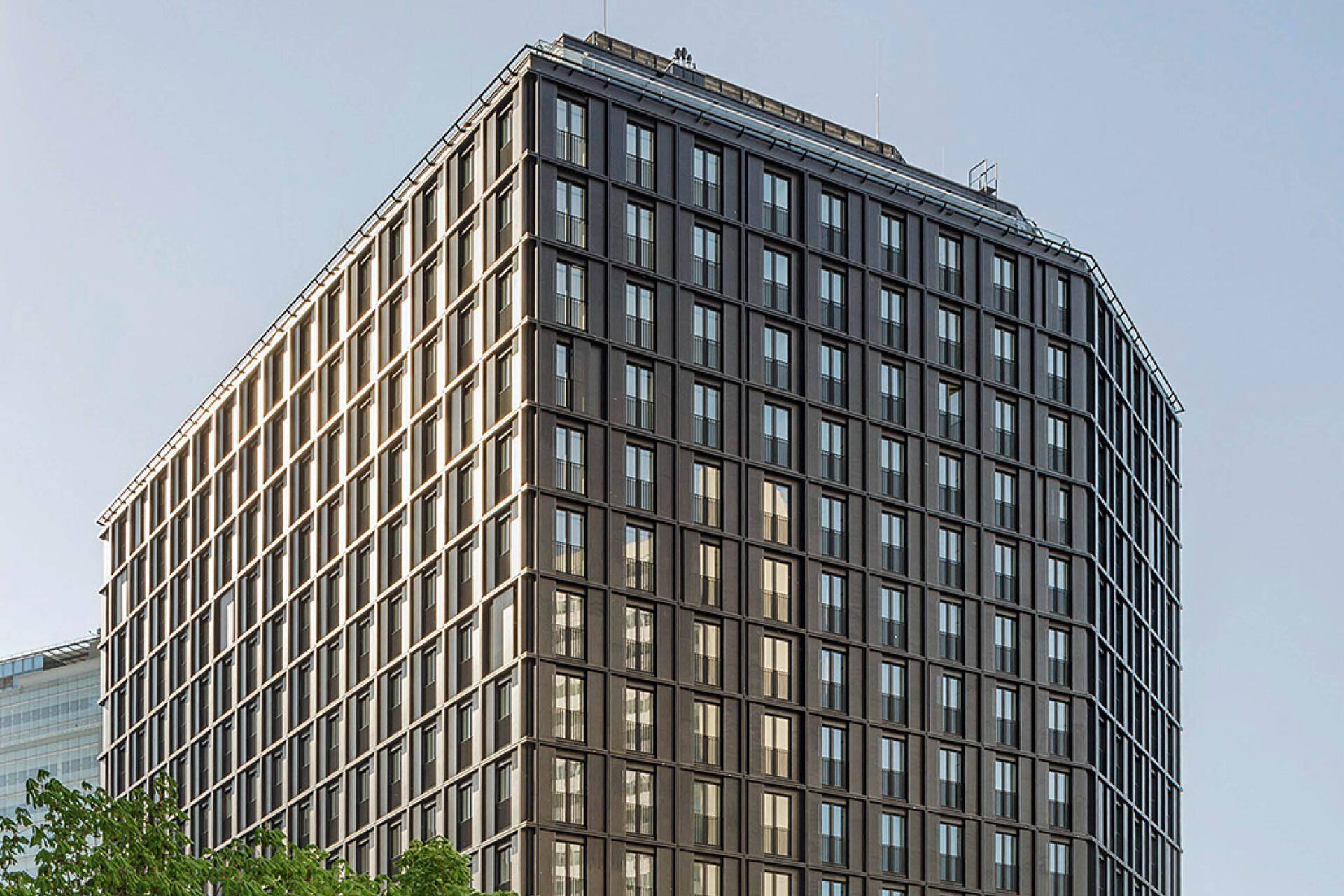 Gesamtaufnahme des modernen Hochhauses mit seiner markanten Architektur unter blauem Himmel.