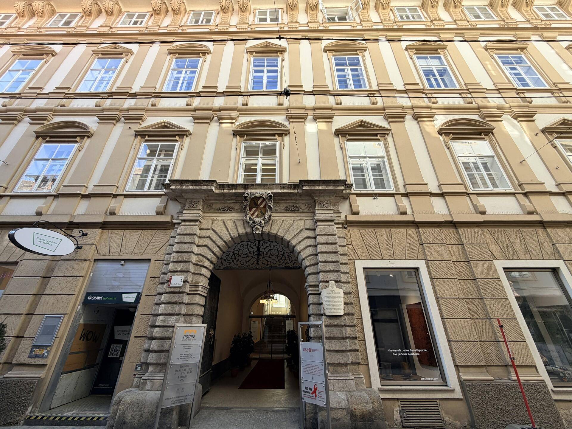 Detailansicht der historischen Fassade mit dem Haupteingang und großen Fenstern.