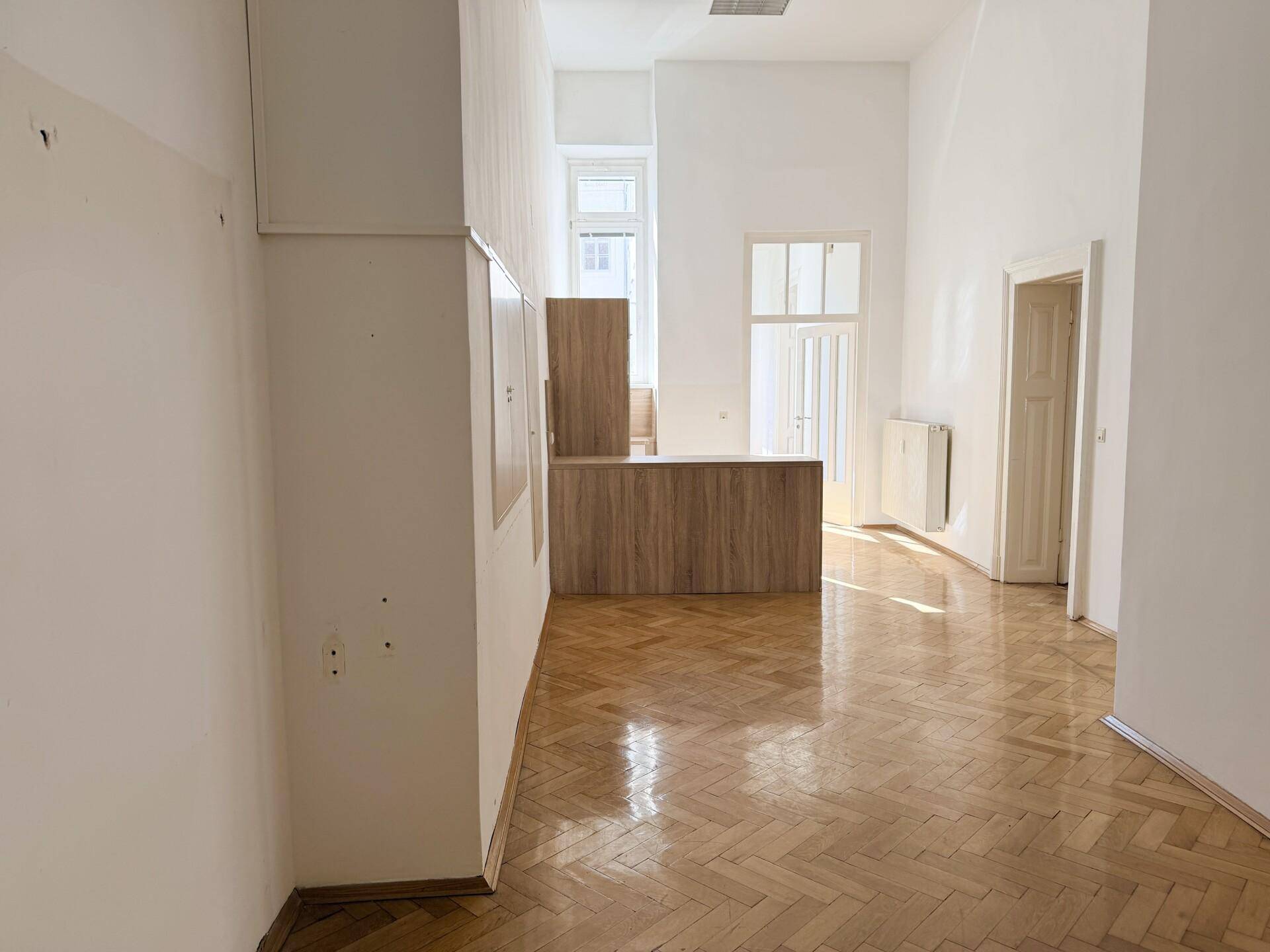 Offener Bürobereich mit Holzboden, hohen Decken und einer modernen Holztheke.