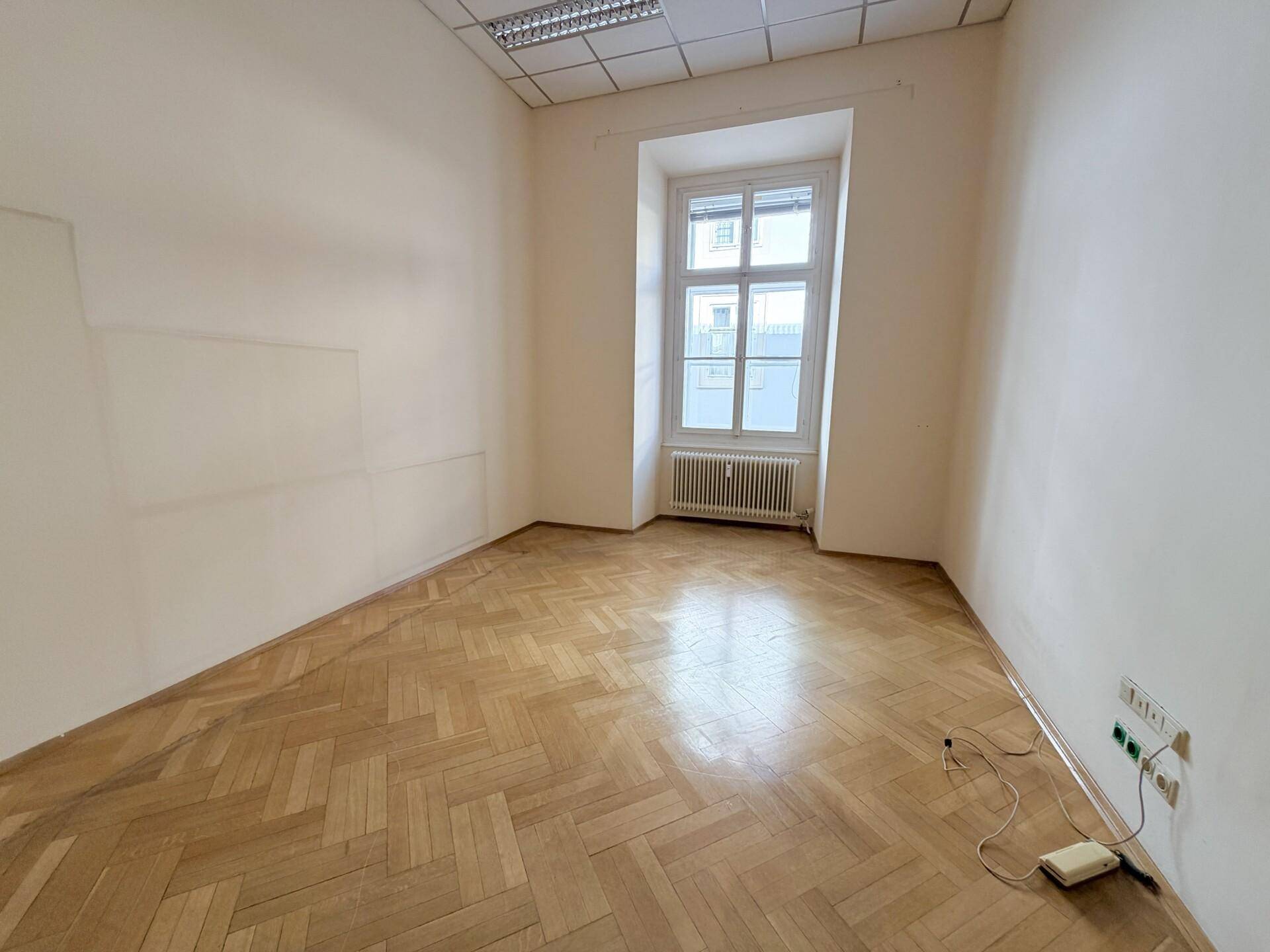 Kleineres Büro mit Fischgrätparkett, einem Fenster und einfacher Ausstattung.