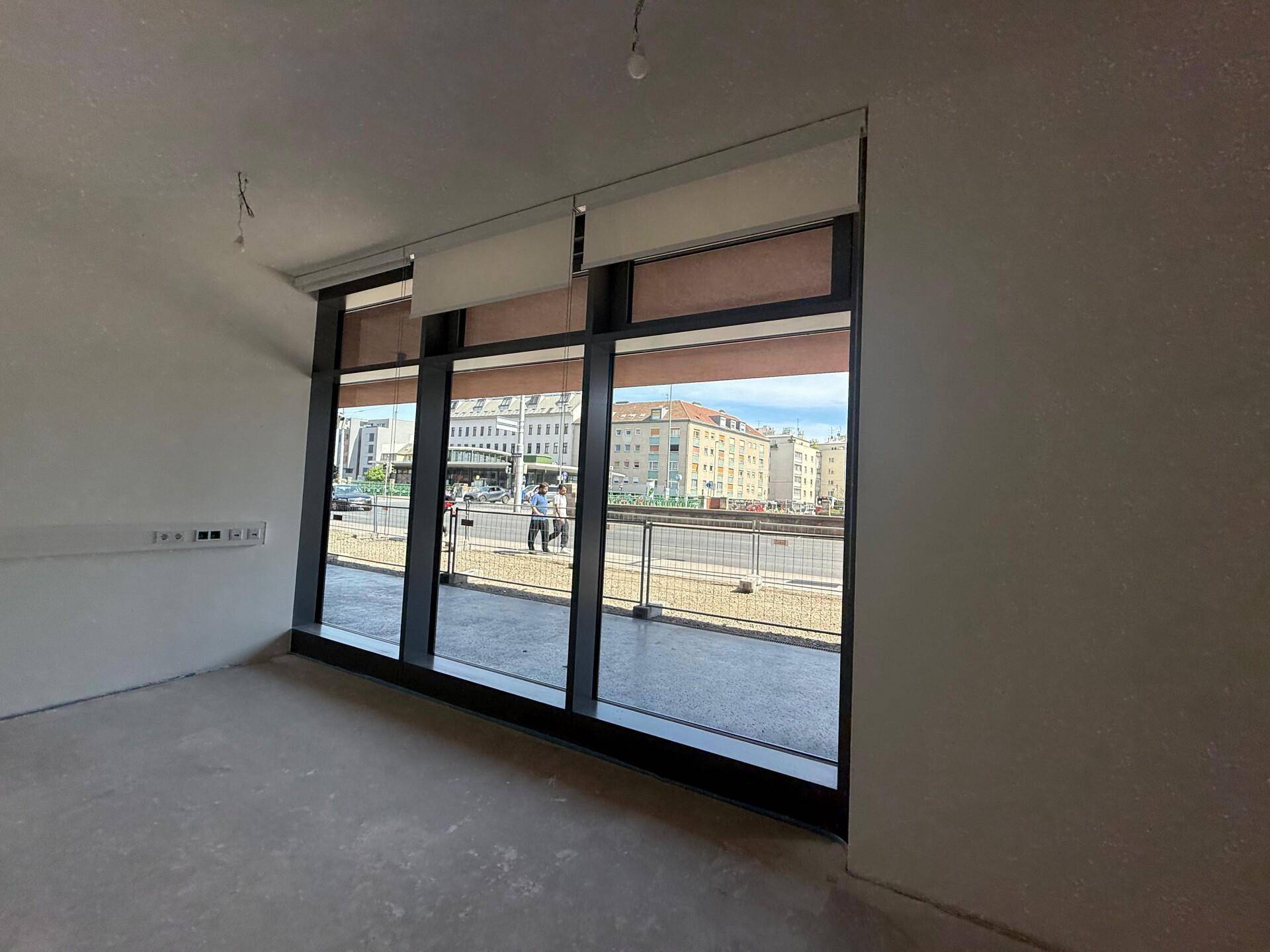 Große Fensterfront mit Blick auf die Stadtstraße in einem unmöblierten Gewerberaum.