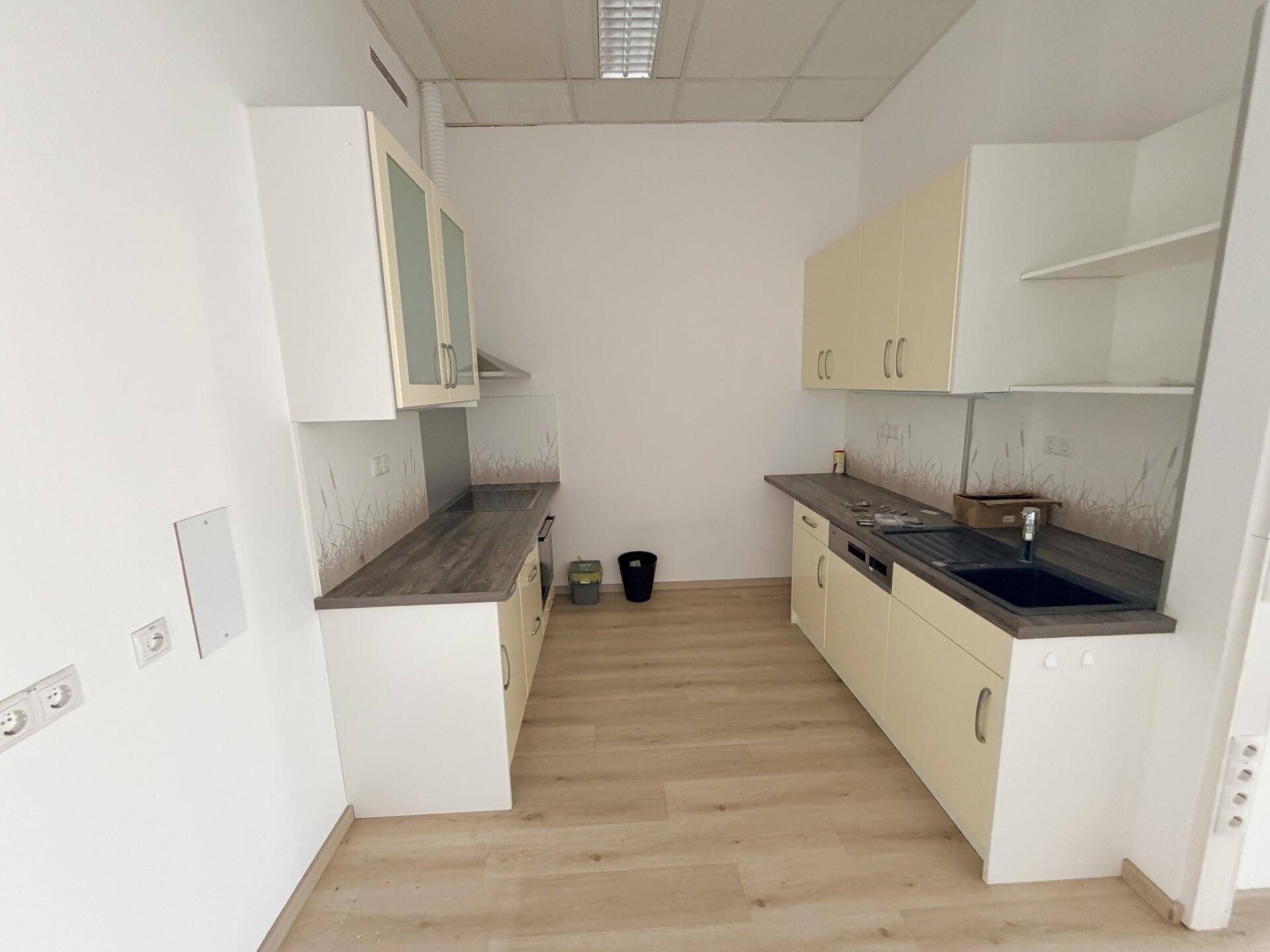 Funktionale Küchenzeile mit hellen Schränken, Spüle und Arbeitsplatten, ideal für eine Büroküche.
