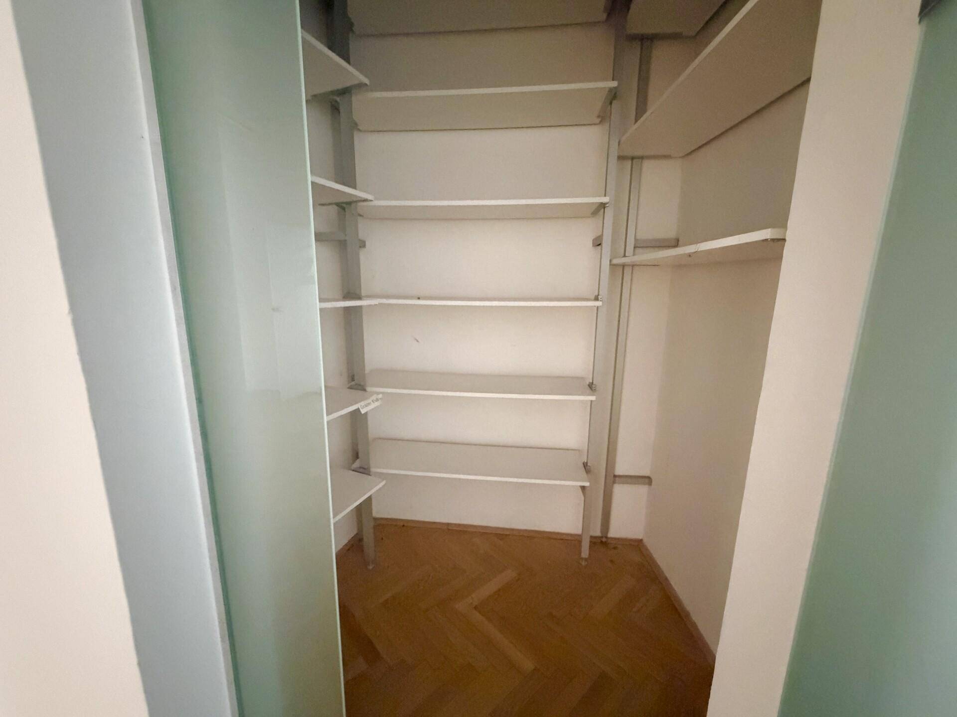 Praktischer Abstellraum mit mehreren Regalböden und Fischgrätparkettboden für zusätzlichen Stauraum.