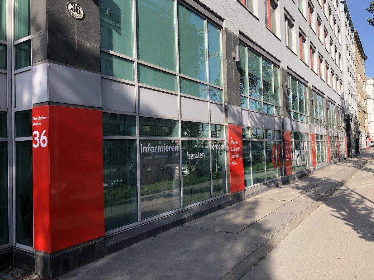 Moderne Geschäftsfassade mit großen Schaufenstern und roten Akzenten an der Straßenseite.