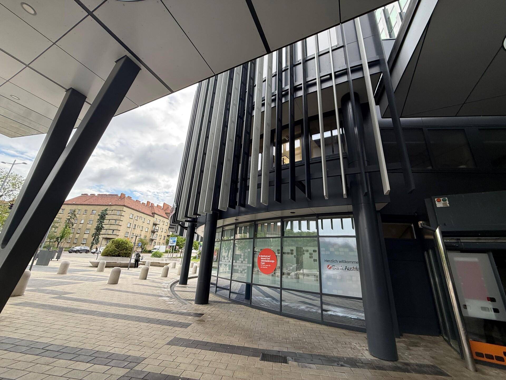 Blick auf die moderne Fassade eines Geschäftsgebäudes mit vertikalen Lamellen und umliegendem Bürgersteig.