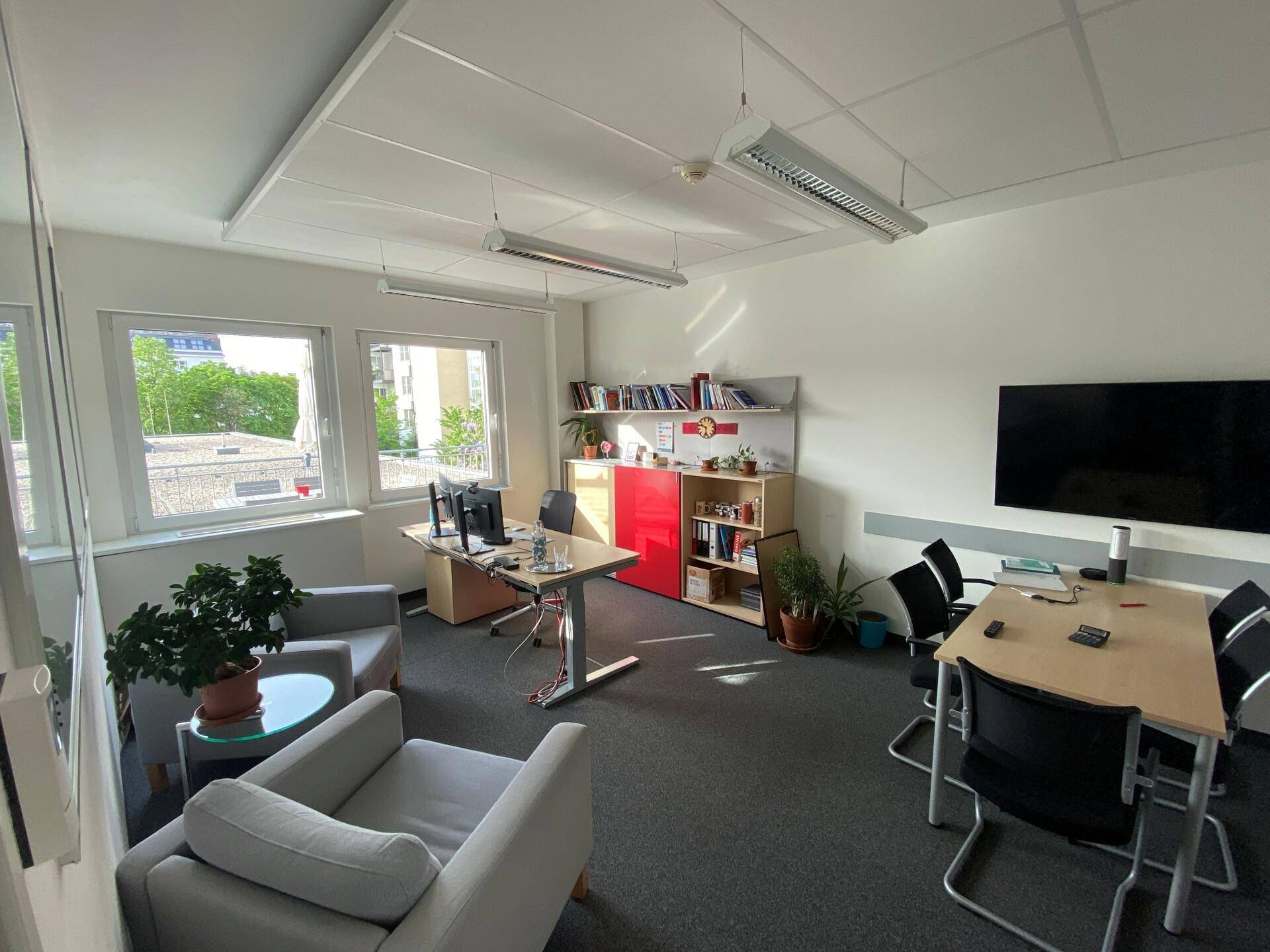 Helles Büro mit Besprechungstisch, bequemen Sesseln und Blick auf die Umgebung.