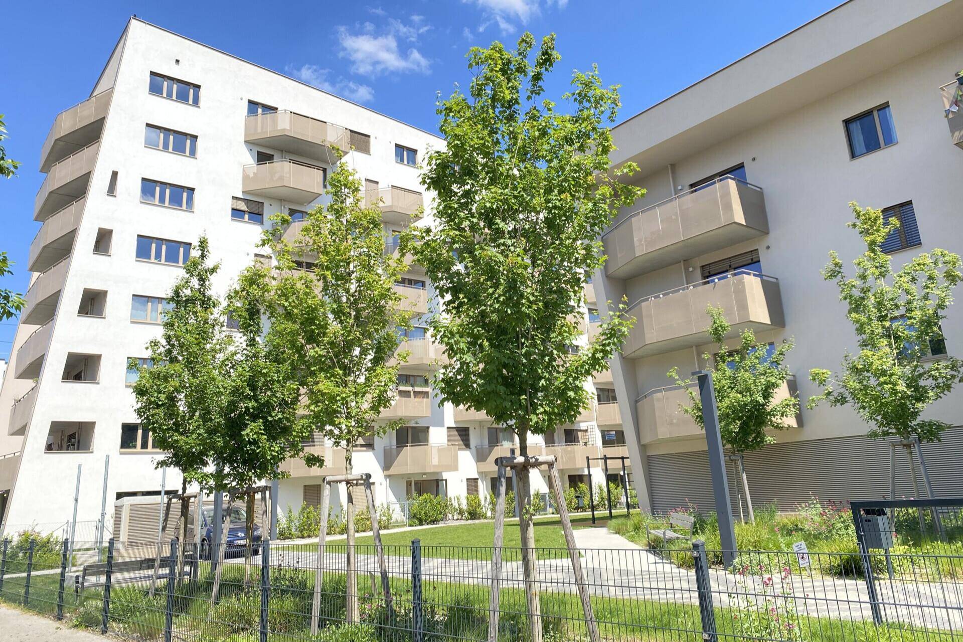Weitläufige Außenansicht der modernen Wohnanlage mit vielen Balkonen und Grünflächen.