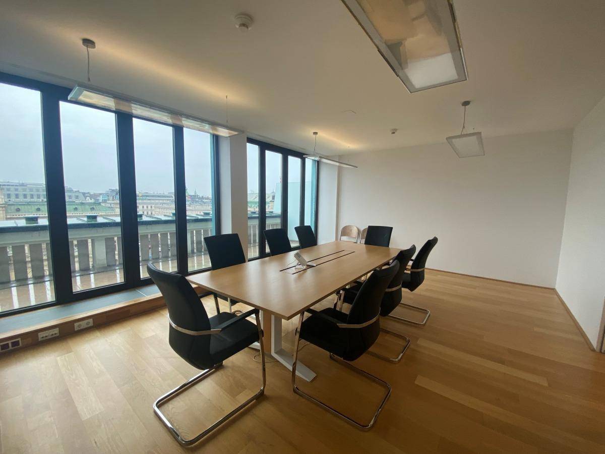 Moderner Konferenzraum mit großem Holztisch, bequemen Stühlen und raumhohen Fenstern mit Weitblick.