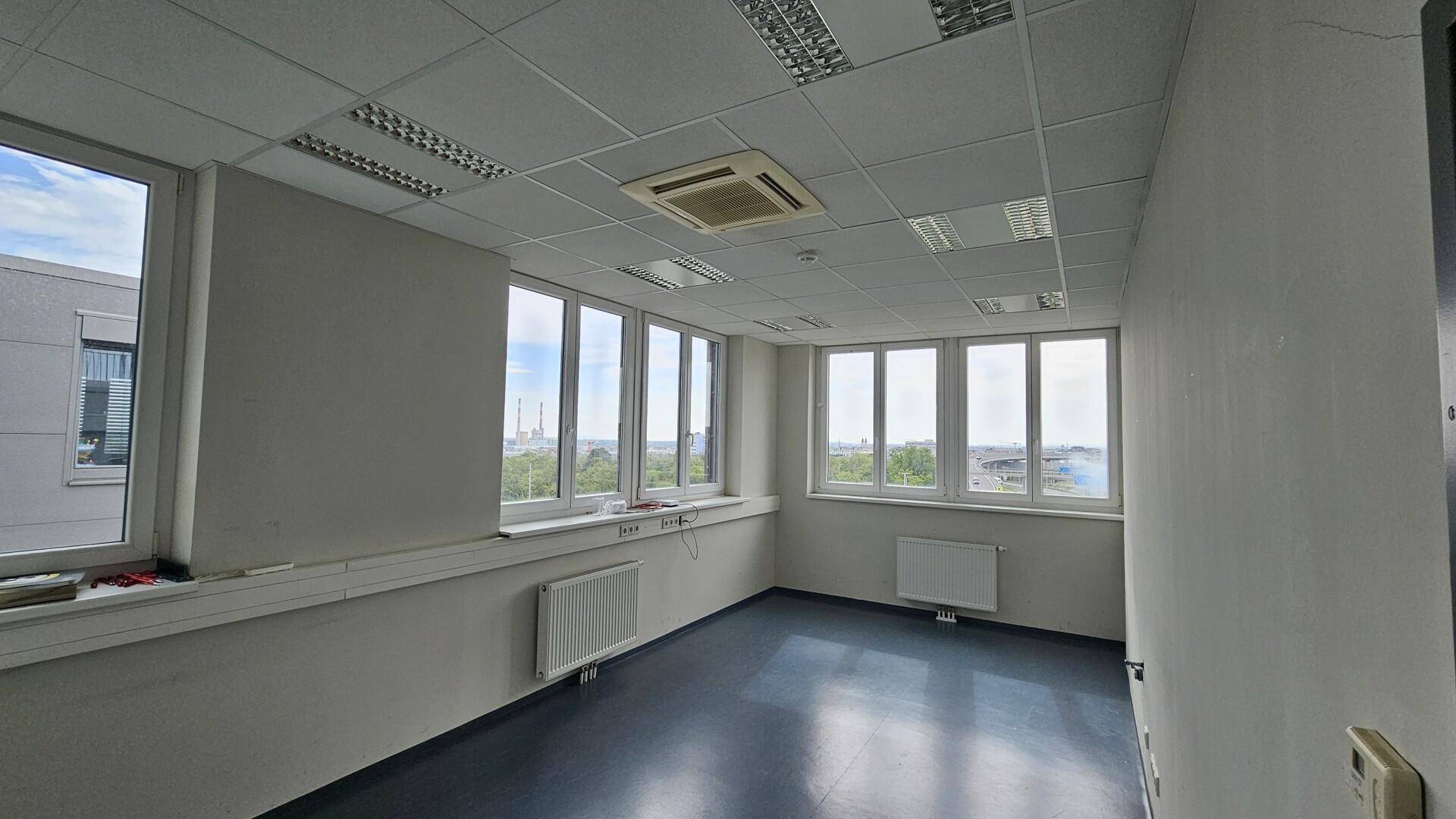 Helles, leeres Büro mit vielen Fenstern, die einen weiten Blick über die Stadt bieten.