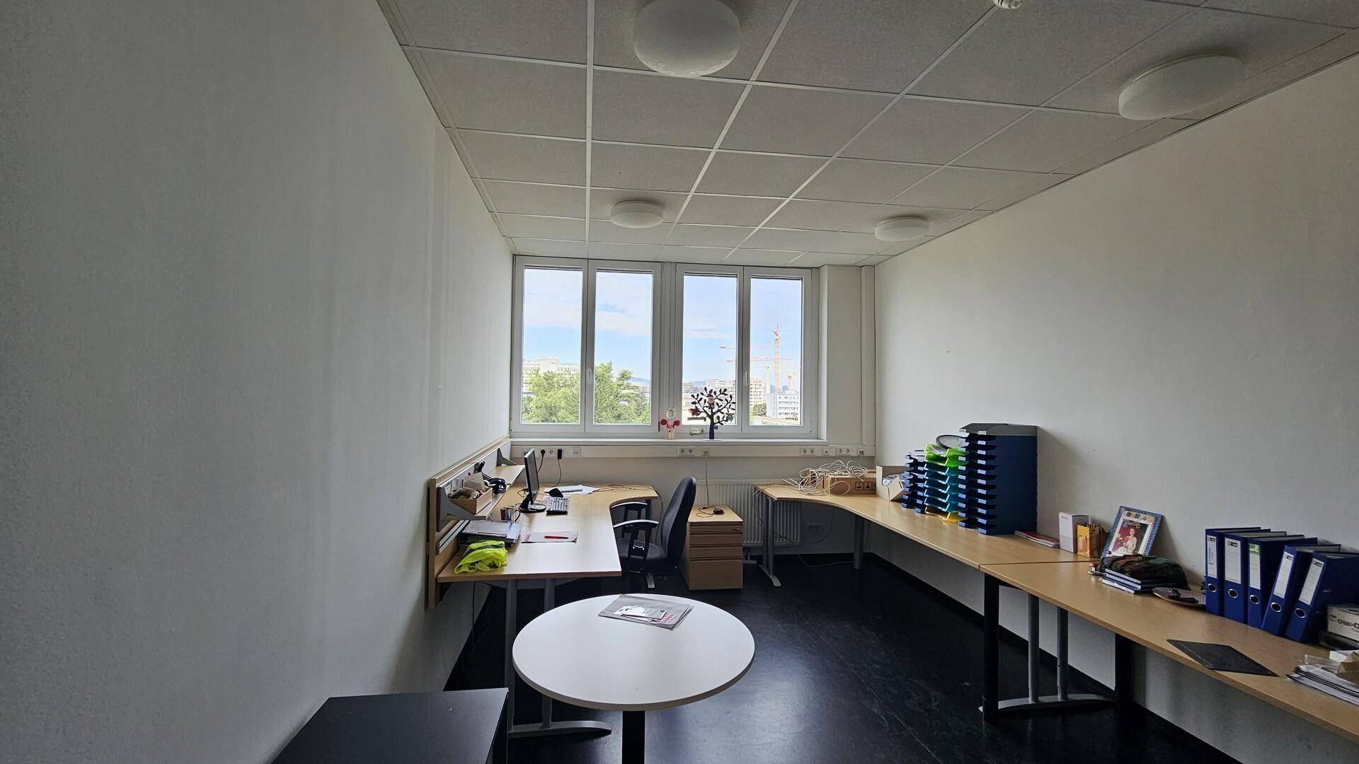 Helles Büro mit mehreren Arbeitsplätzen, Schreibtischen und Blick nach draußen.