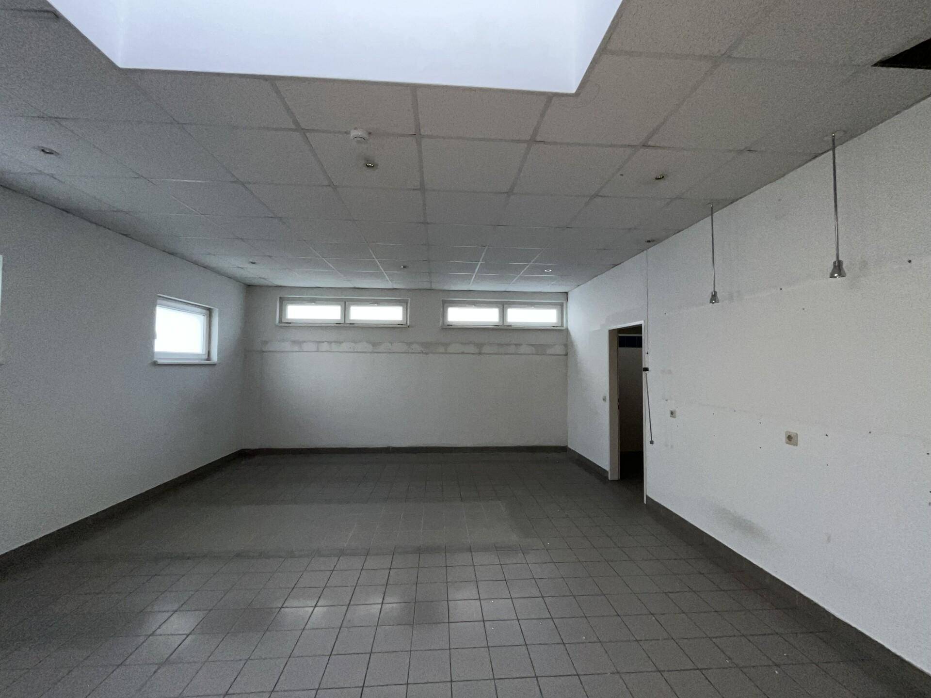 Leerer Raum mit Fliesenboden und kleinen Fenstern, geeignet für Lagerung oder Nebenräume.