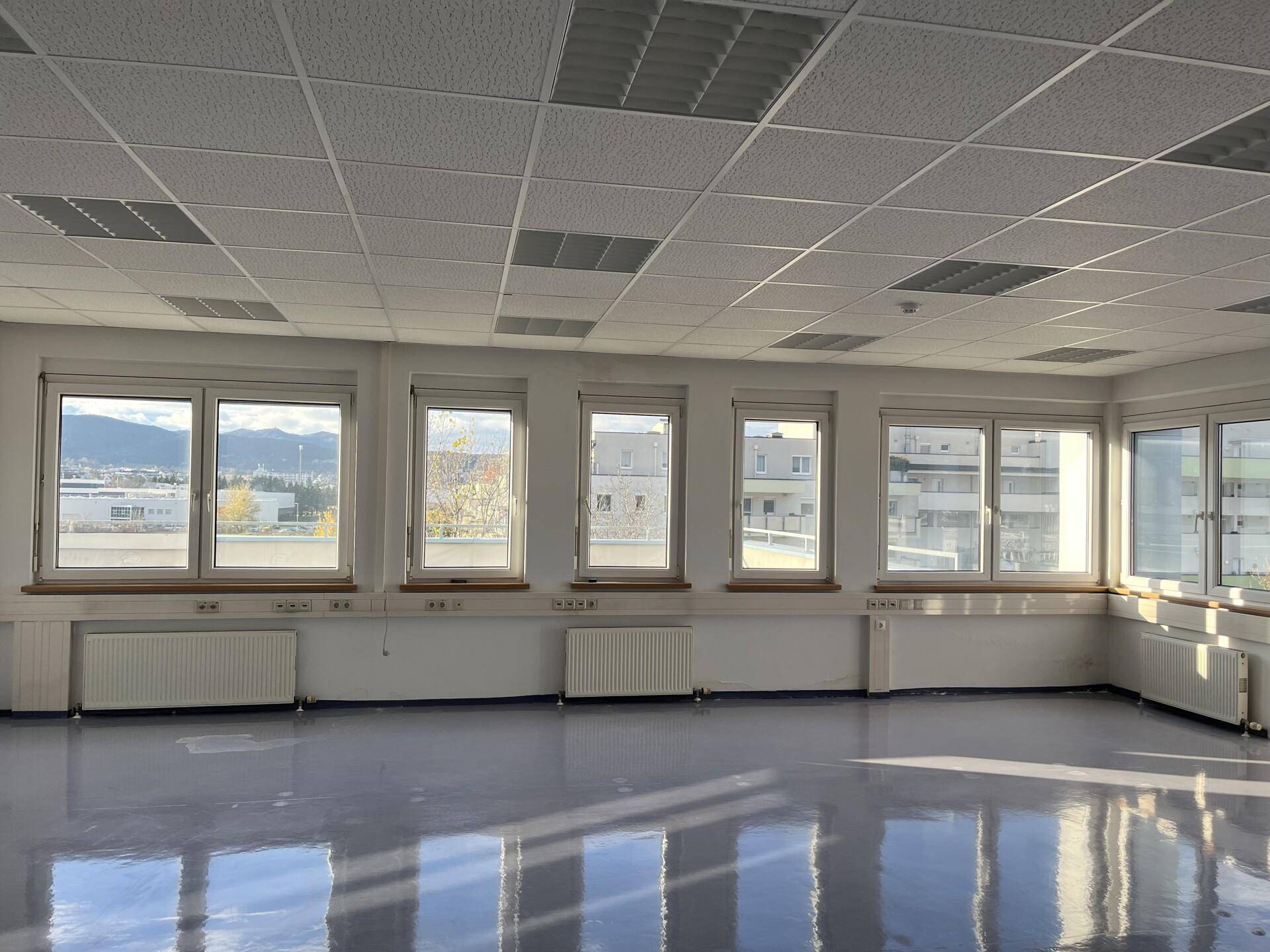 Helles Büro mit zahlreichen Fenstern, die einen weiten Blick auf die Stadt und die Berge bieten.