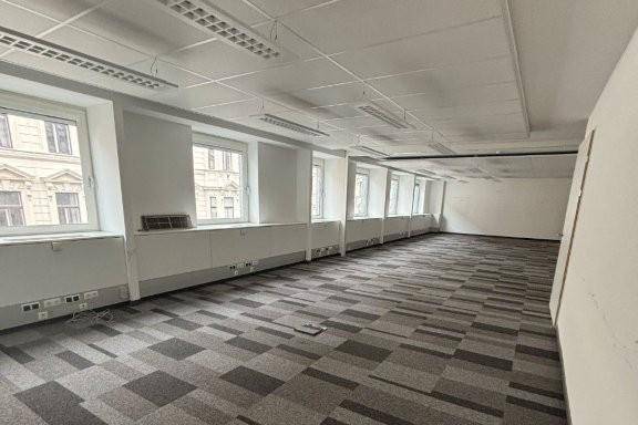 Geräumiges Büro mit Teppichboden und vielen Fenstern, ideal für Arbeitsplätze in einem modernen Gebäude.