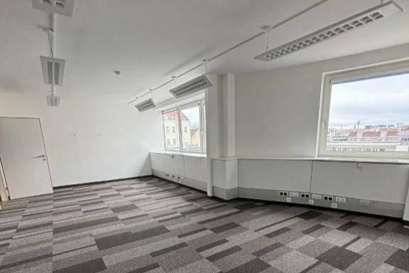 Helles Büro mit Teppichboden und Blick auf die Stadt, ausgestattet mit modernen Deckenleuchten.