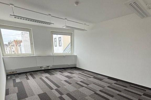 Ruhiges Büro mit Teppichboden und zwei großen Fenstern, ideal für konzentriertes Arbeiten in heller Umgebung.