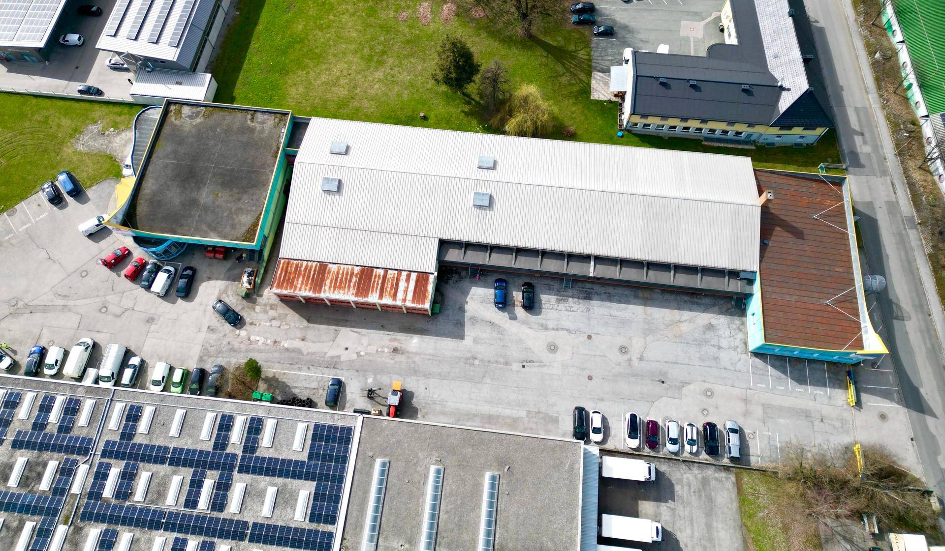 Luftaufnahme eines Industriegebiets mit mehreren Gebäuden, Parkplätzen und Solaranlagen auf den Dächern.
