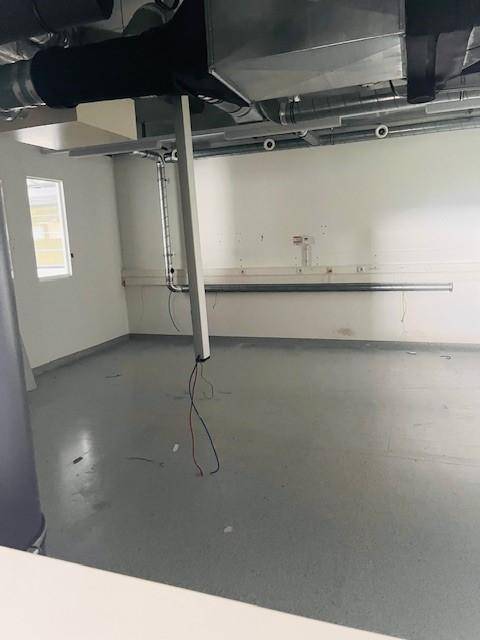 Kleiner Raum mit Betonboden, sichtbaren Rohren und Kabeln, ideal als Lager oder Technikraum.