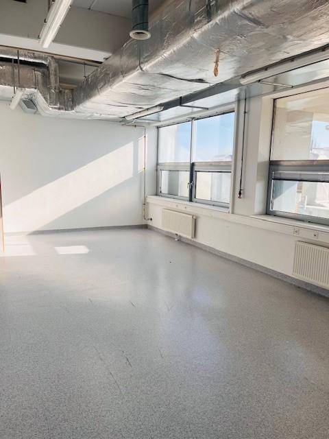 Heller Raum mit Betonboden, großen Fenstern und Heizkörpern, geeignet für Büro oder Werkstatt.
