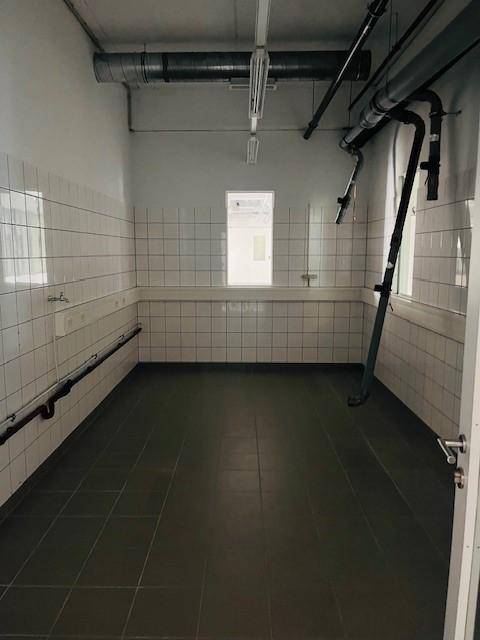 Gefliester Raum mit Waschbecken und sichtbaren Rohren, geeignet als Hauswirtschaftsraum oder kleine Küche.