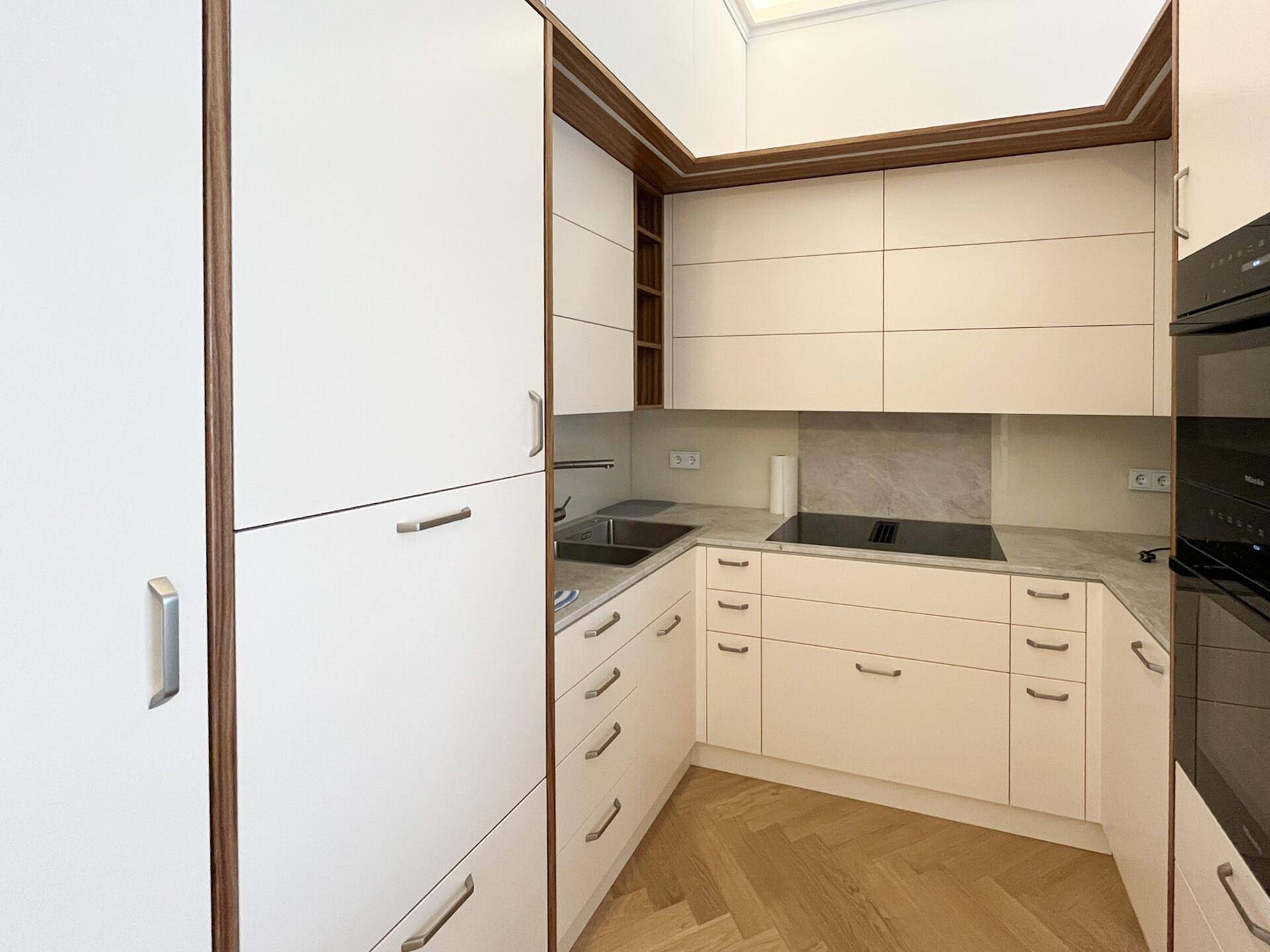 Moderne Einbauküche mit weißen Fronten, Marmorarbeitsplatte und integrierten Geräten.