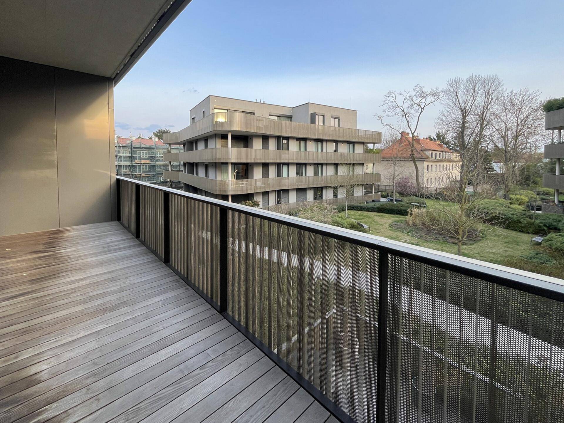 Geräumiger Balkon mit Holzboden und Metallgeländer, bietet einen weiten Blick auf die Umgebung.