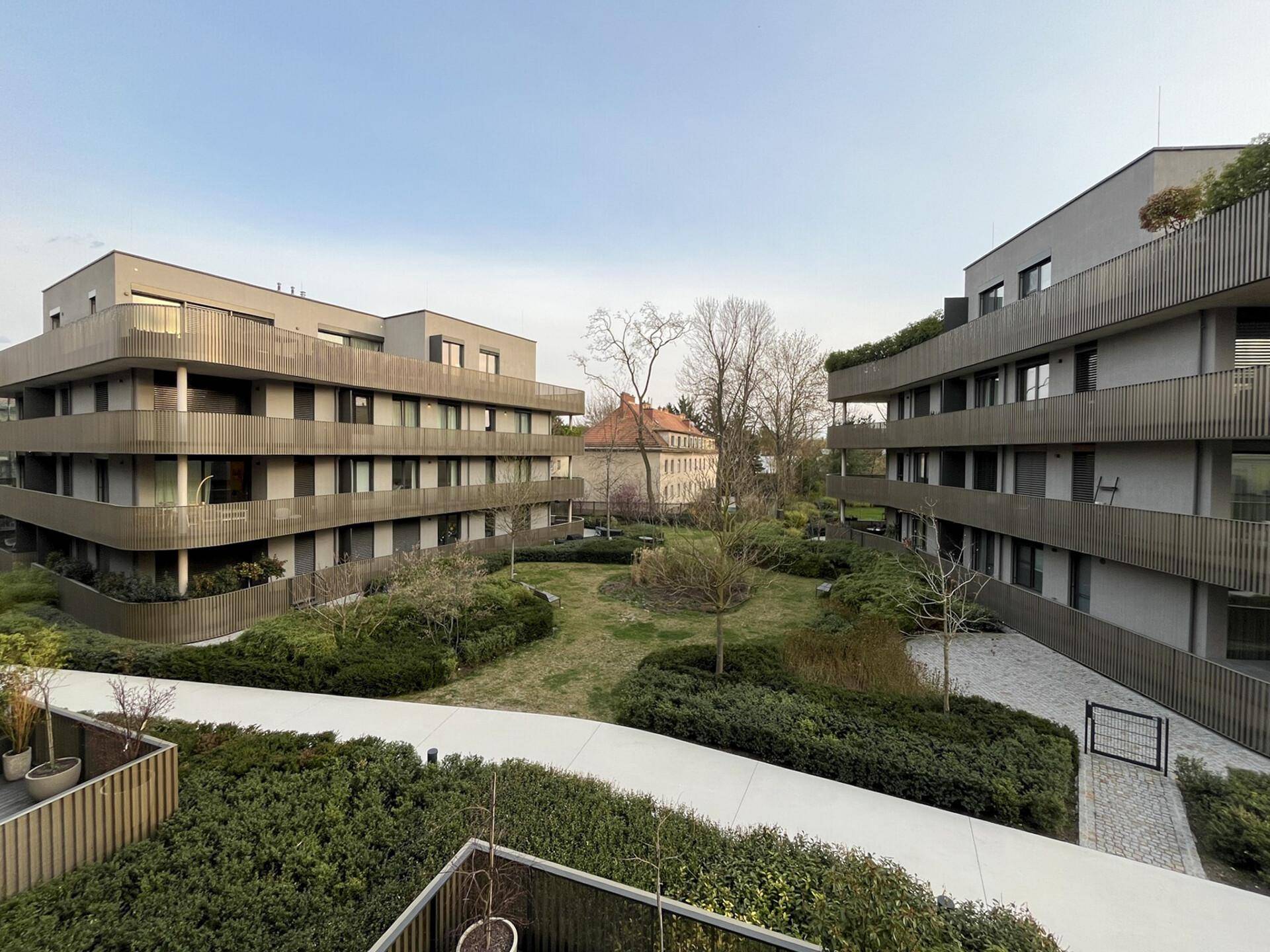 Moderne Wohnanlage mit mehreren Gebäuden und einer weitläufigen, grünen Gartenlandschaft.