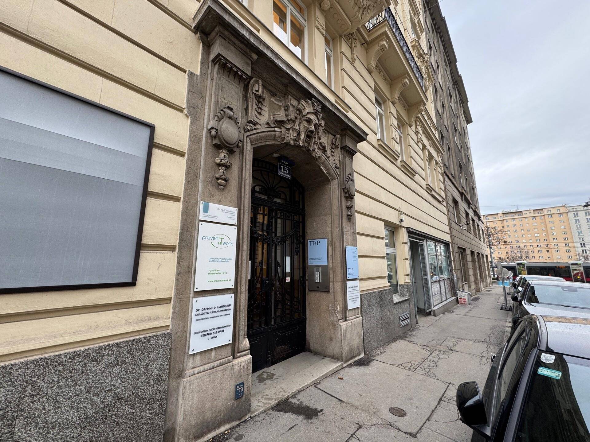 Prunkvoller Gebäudeeingang mit reich verzierten Details und mehreren Firmenschildern an einer städtischen Straße.