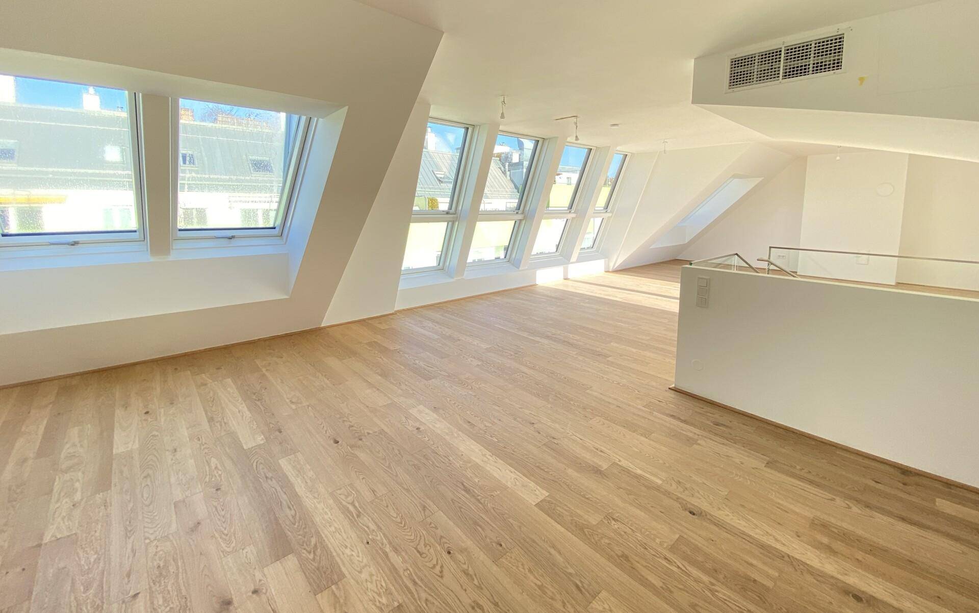 Heller Wohnbereich im Dachgeschoss mit Holzboden und zahlreichen Dachfenstern für viel Tageslicht.