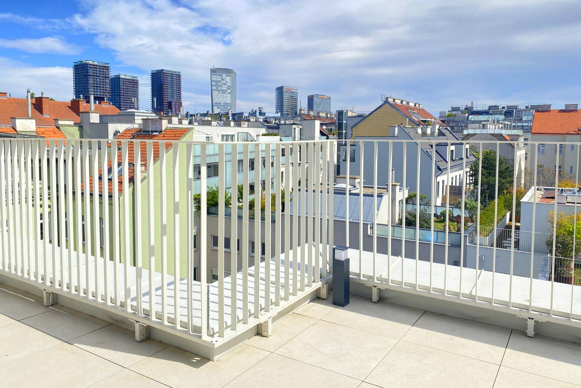 Weitläufige Dachterrasse mit Panoramablick auf die städtische Skyline und umliegende Gebäude.