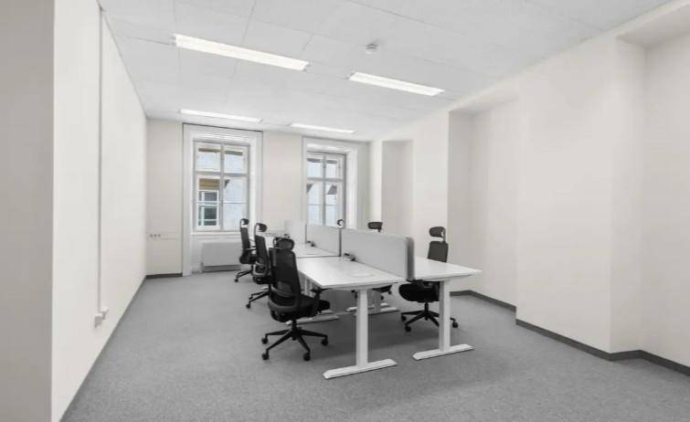 Geräumiges Büro mit mehreren Arbeitsplätzen, Teppichboden und viel Tageslicht durch Fenster.
