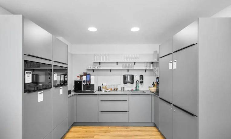Moderne Küchenzeile mit grauen Schränken, Holzboden und integrierten Geräten.