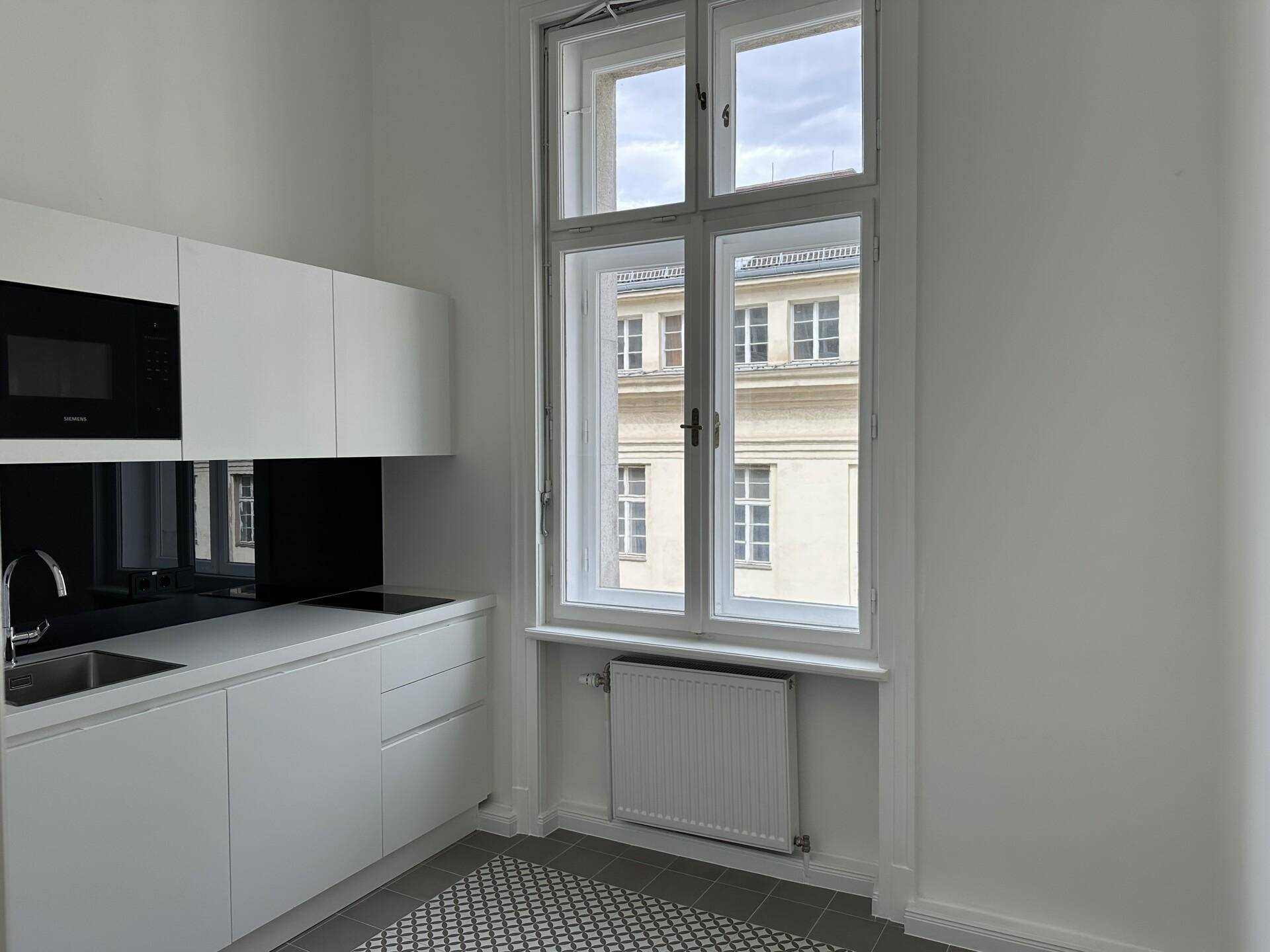 Moderne weiße Küchenzeile mit integrierter Mikrowelle und Blick auf die umliegenden Gebäude.
