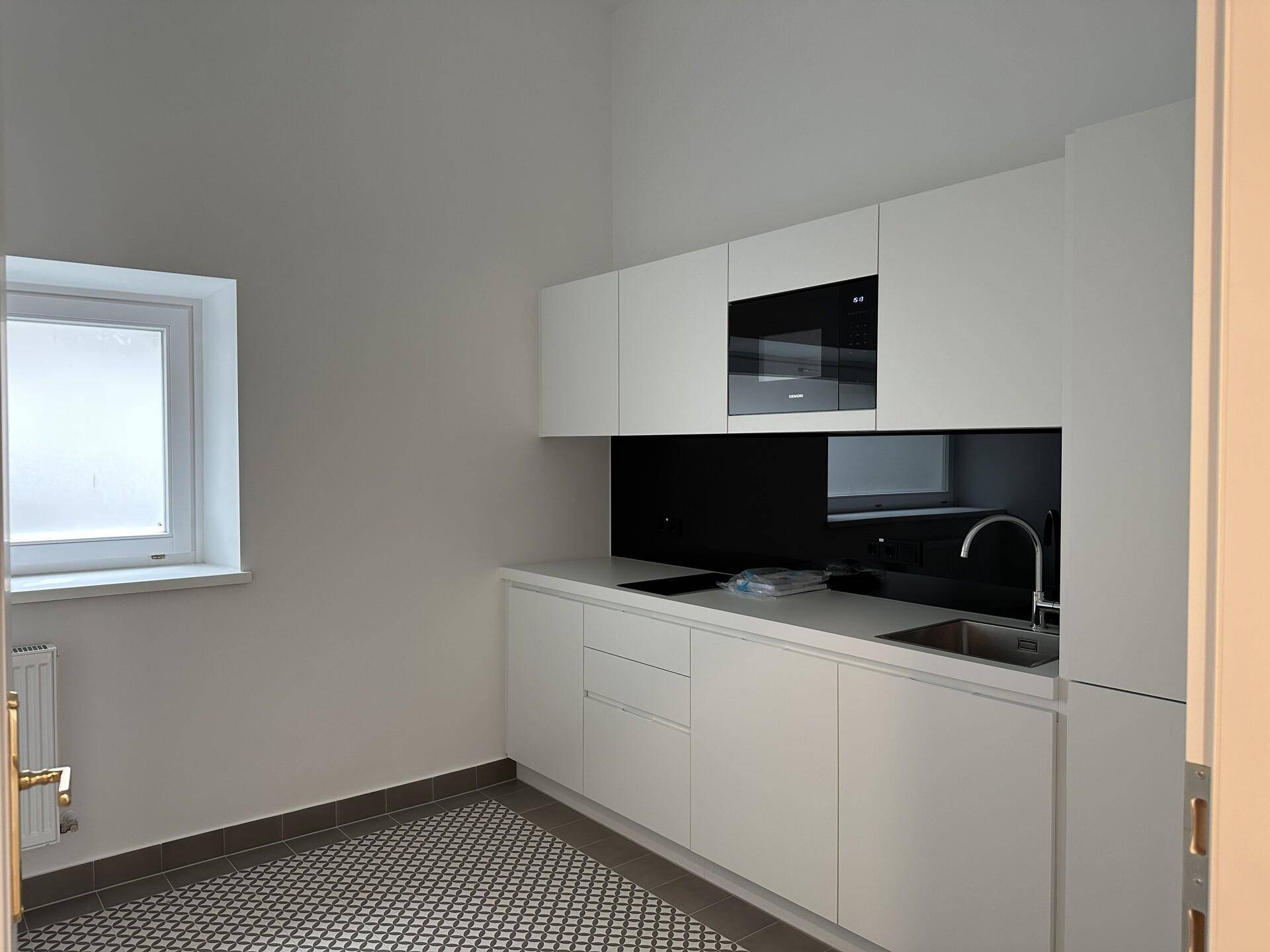 Moderne weiße Küchenzeile mit integrierter Mikrowelle und einem kleinen Fenster.
