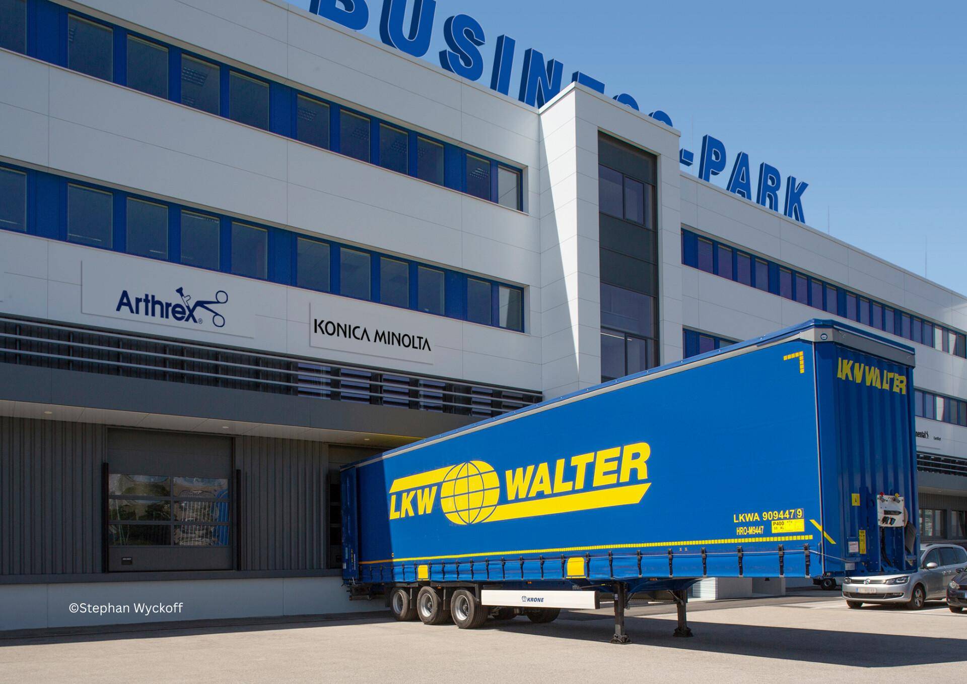 Modernes Geschäftsgebäude mit LKW-Laderampe und blauer LKW-Walter-Zugmaschine.