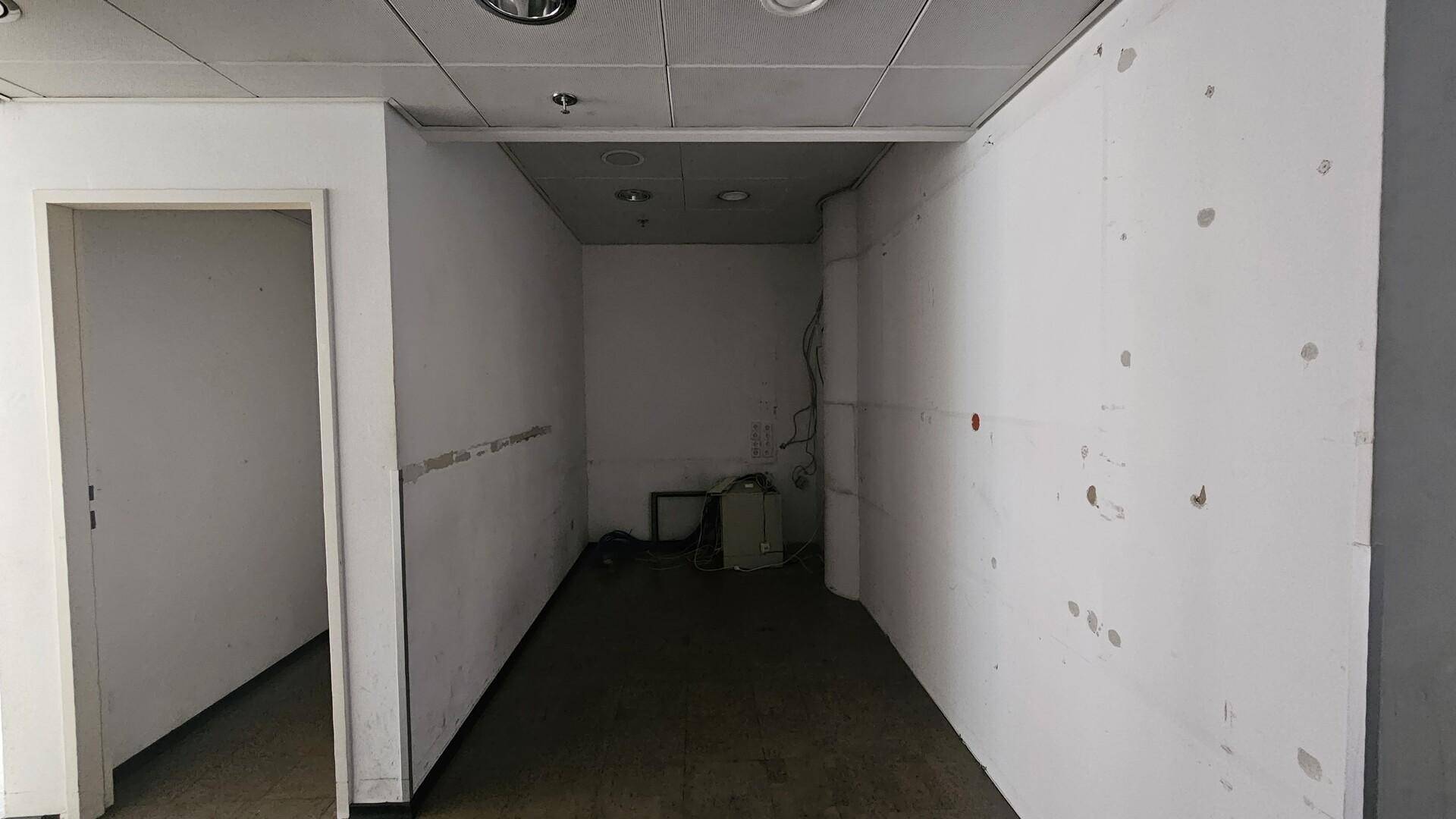 Kleiner, leerer Raum mit weißen Wänden und dunklem Boden, möglicherweise als Abstellraum nutzbar.
