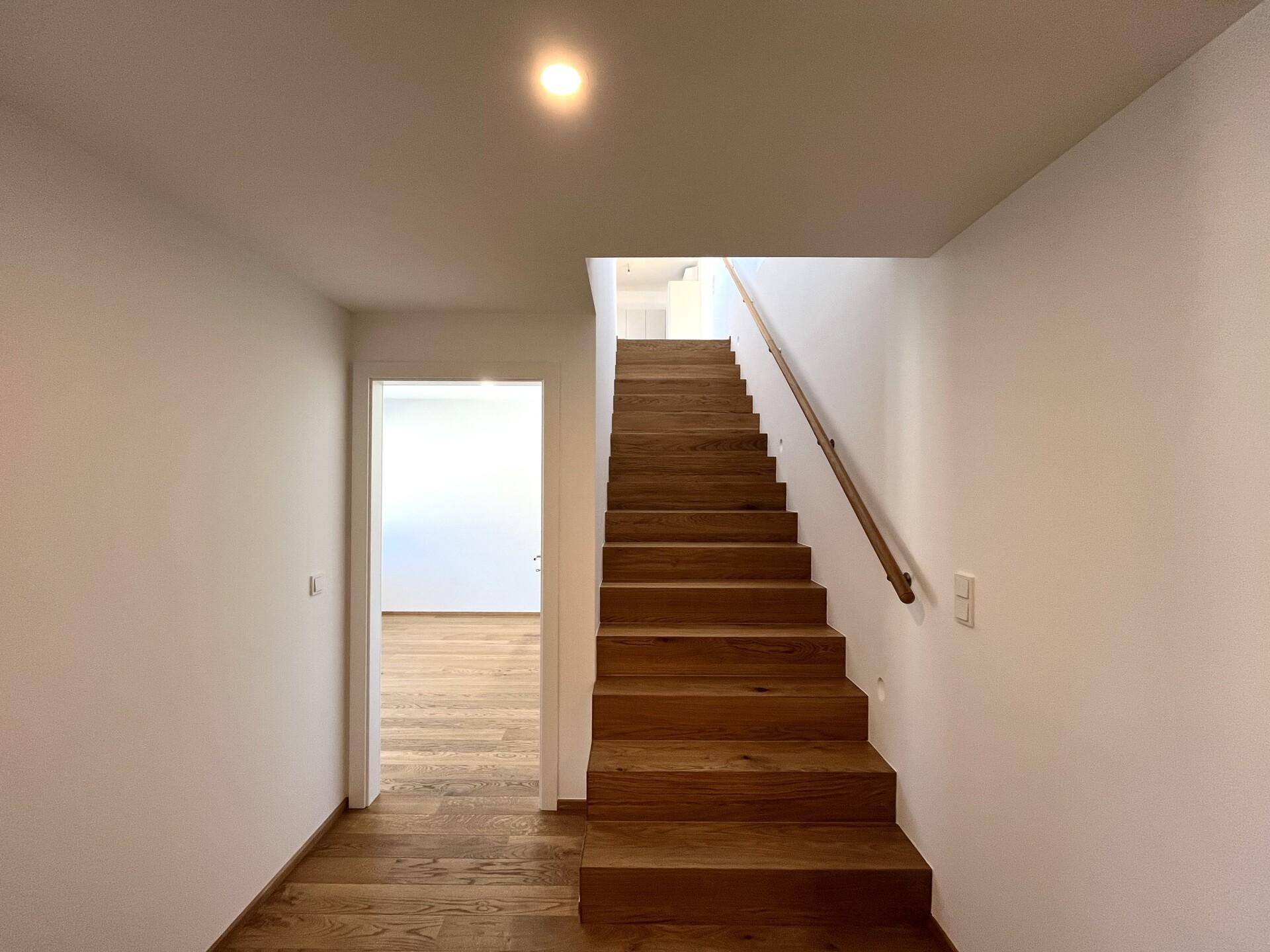 Heller Flur mit Holztreppe, die in die obere Etage führt, und passendem Holzboden.