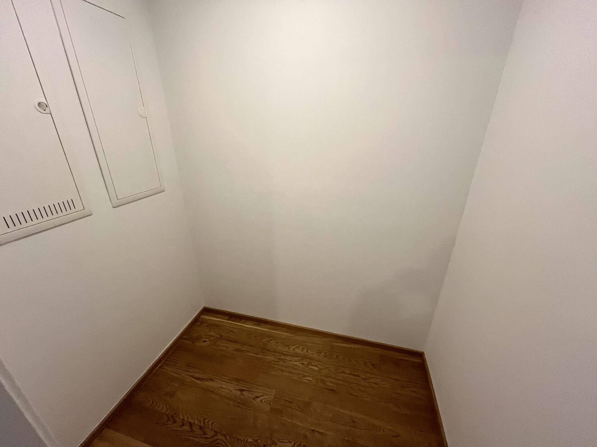 Kleiner Abstellraum mit Holzboden und weißen Wänden, ideal für zusätzlichen Stauraum im Apartment.