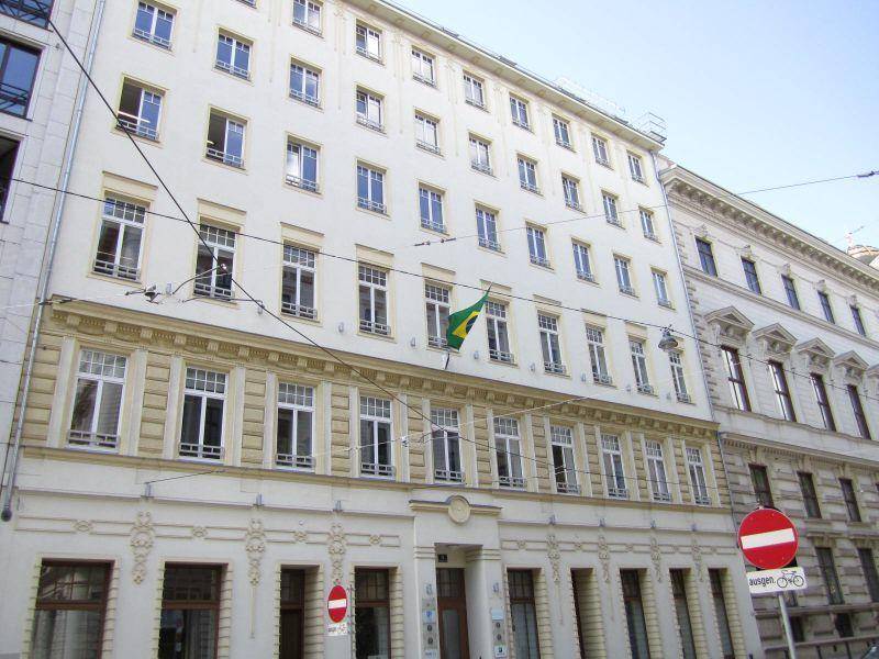 Klassische Fassade eines Mehrfamilienhauses mit vielen Fenstern und einer brasilianischen Flagge.
