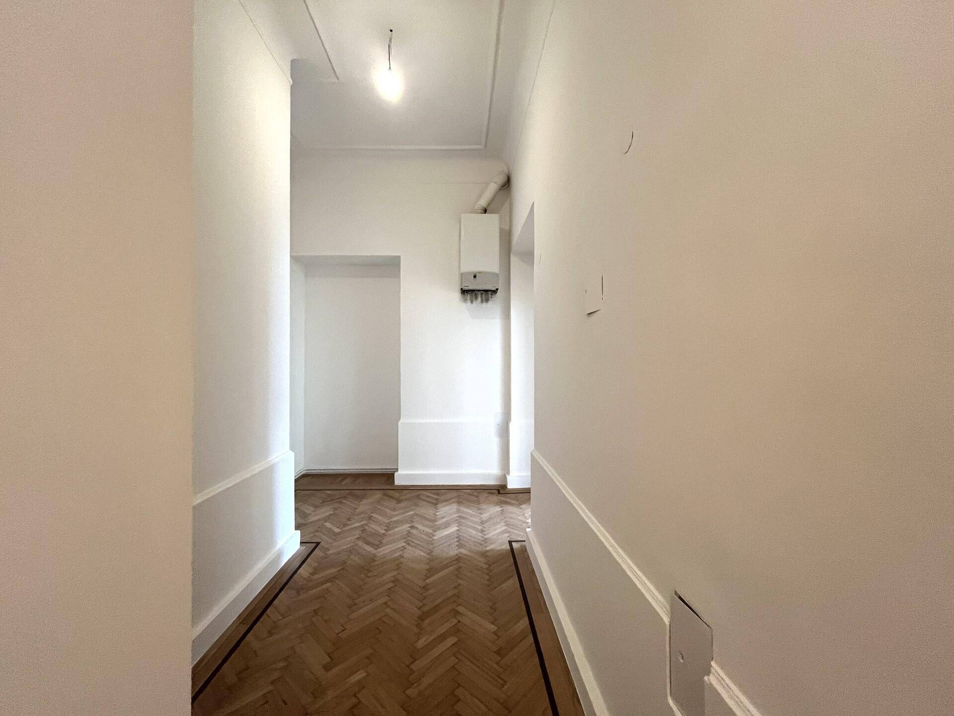 Heller Flur mit Fischgrätparkett und einem an der Wand montierten Heizkessel.