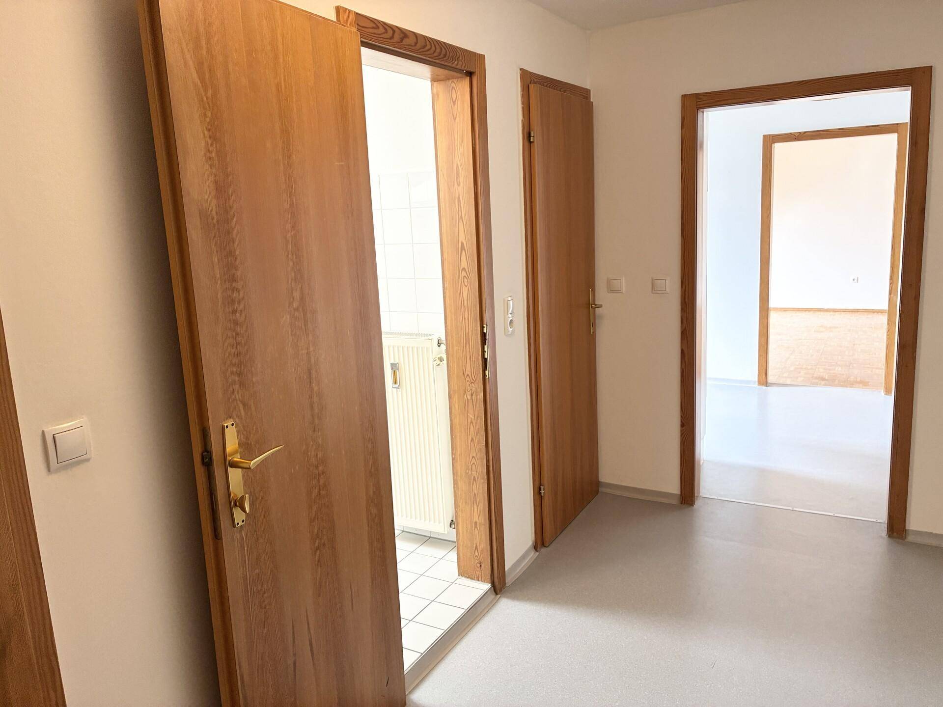 Heller Flur mit mehreren Holztüren, die zu den angrenzenden Zimmern führen.