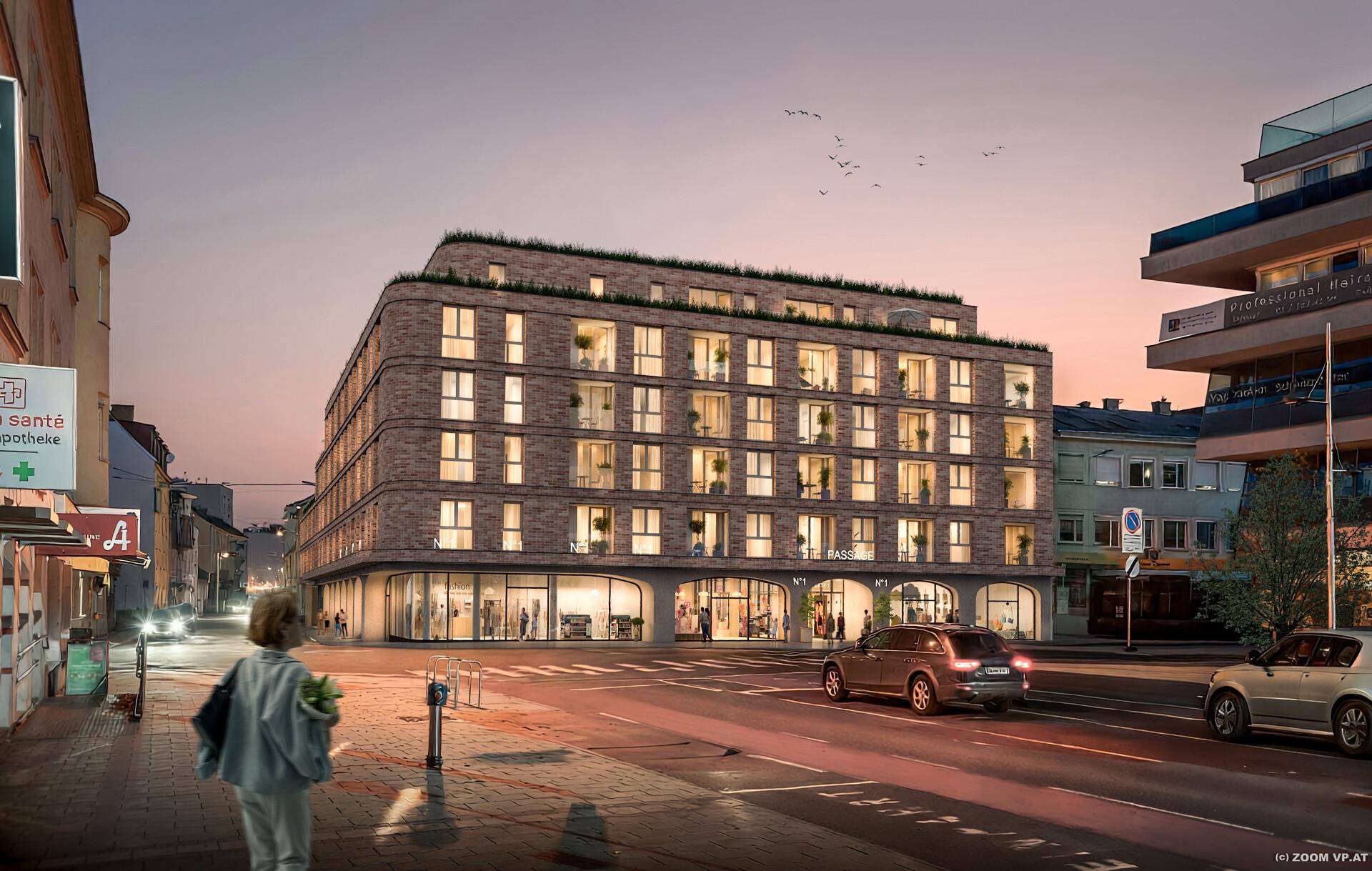 Moderne Wohnanlage mit Geschäften im Erdgeschoss und beleuchteter Fassade bei Sonnenuntergang.