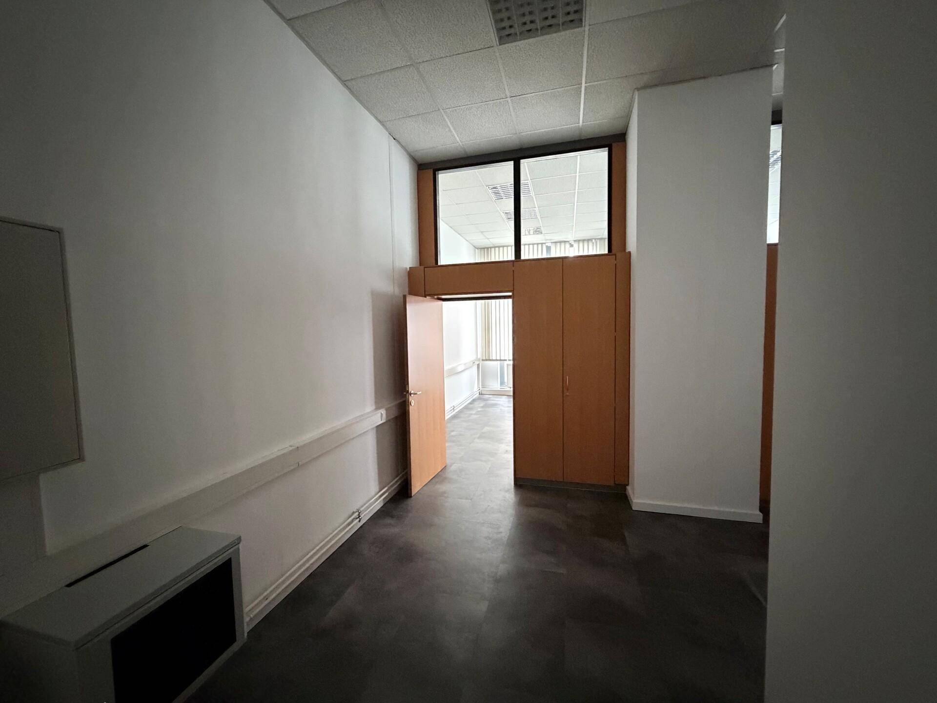 Funktionaler Flur mit dunklem Vinylboden und weißen Wänden, der zu weiteren Büroräumen führt.