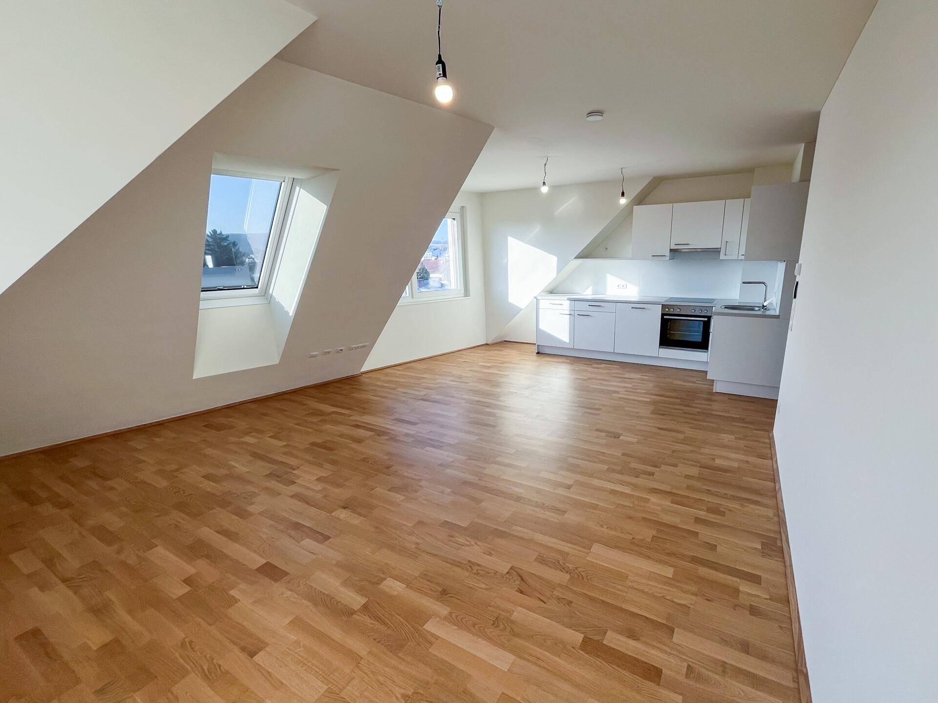 Geräumiger Wohnbereich mit offener Küche, Parkettboden und Dachfenstern.